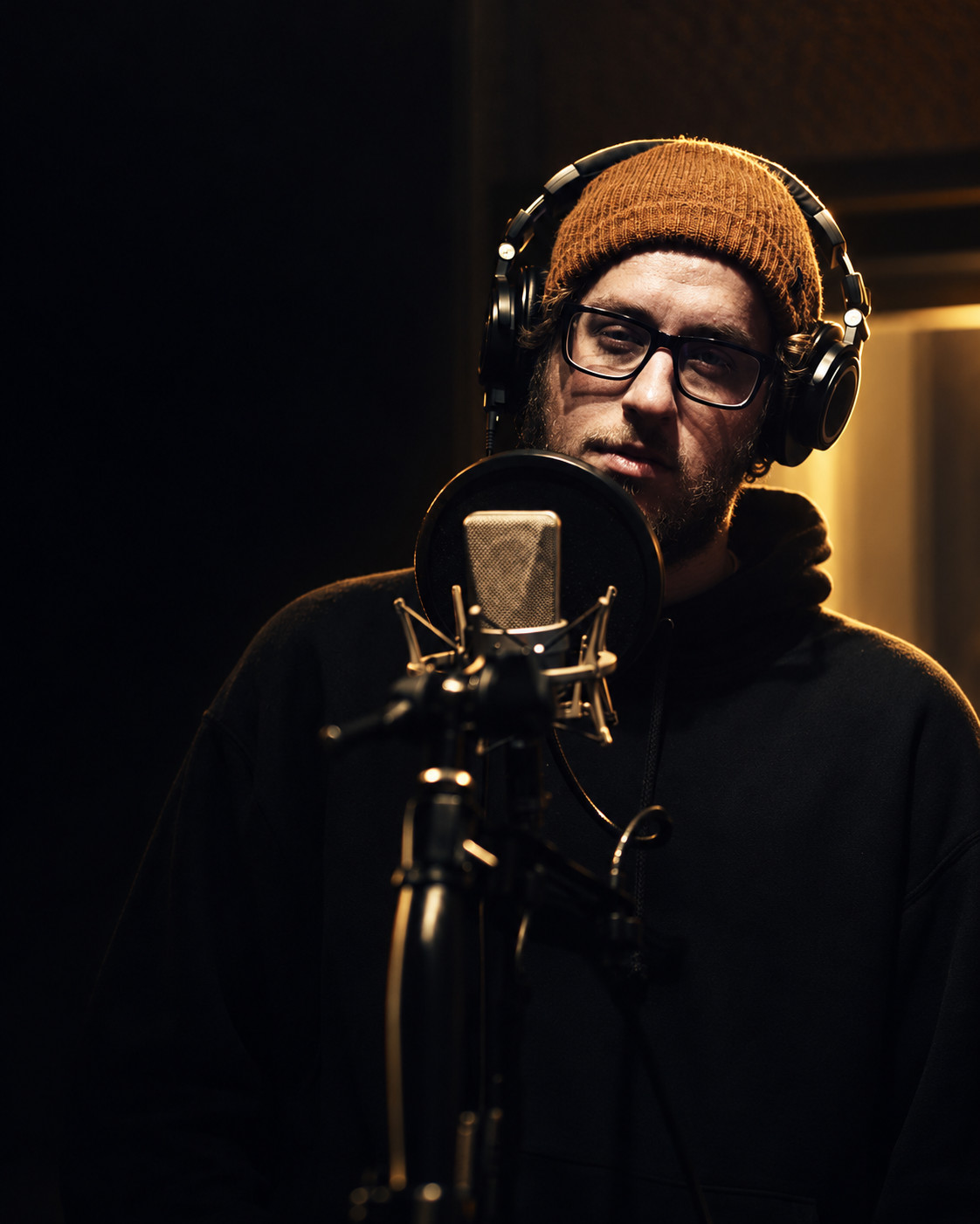 Austin Milby at a microphone in a recording booth